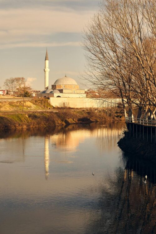 Peaceful Ottoman mosque silhouette reflecting on calm water at sunset evoking spiritual stillness