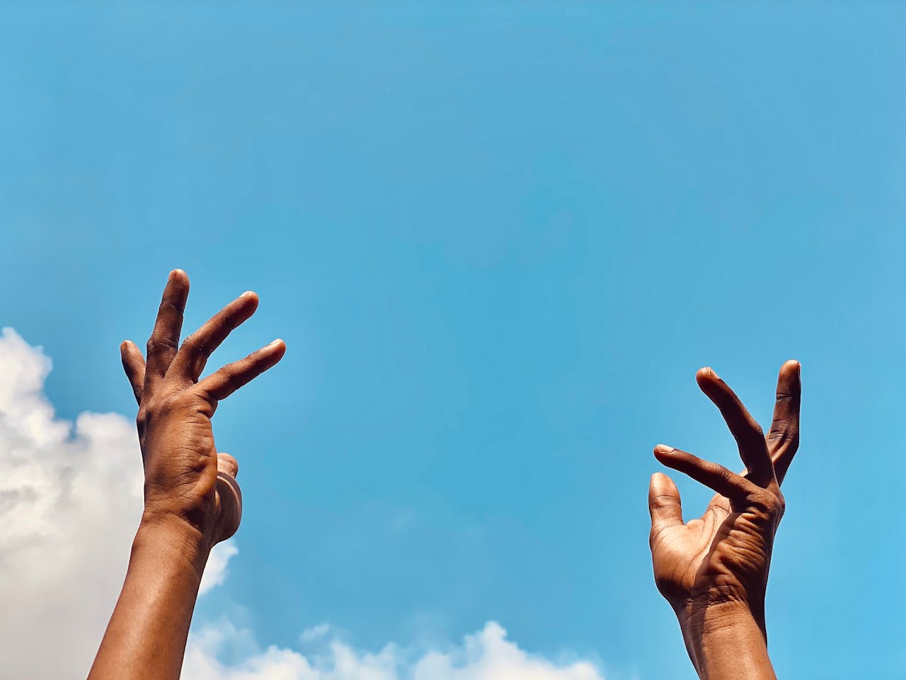 Open palm raised toward a vibrant blue sky symbolizing gratitude and supplication