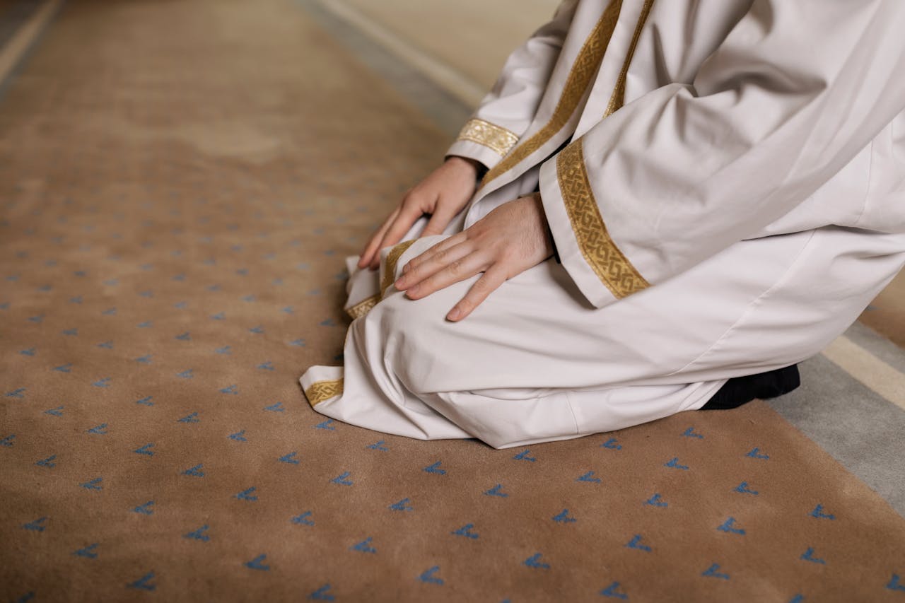 Muslim man kneeling in prayer on a traditional rug while practicing dhikr and remembrance of Allah