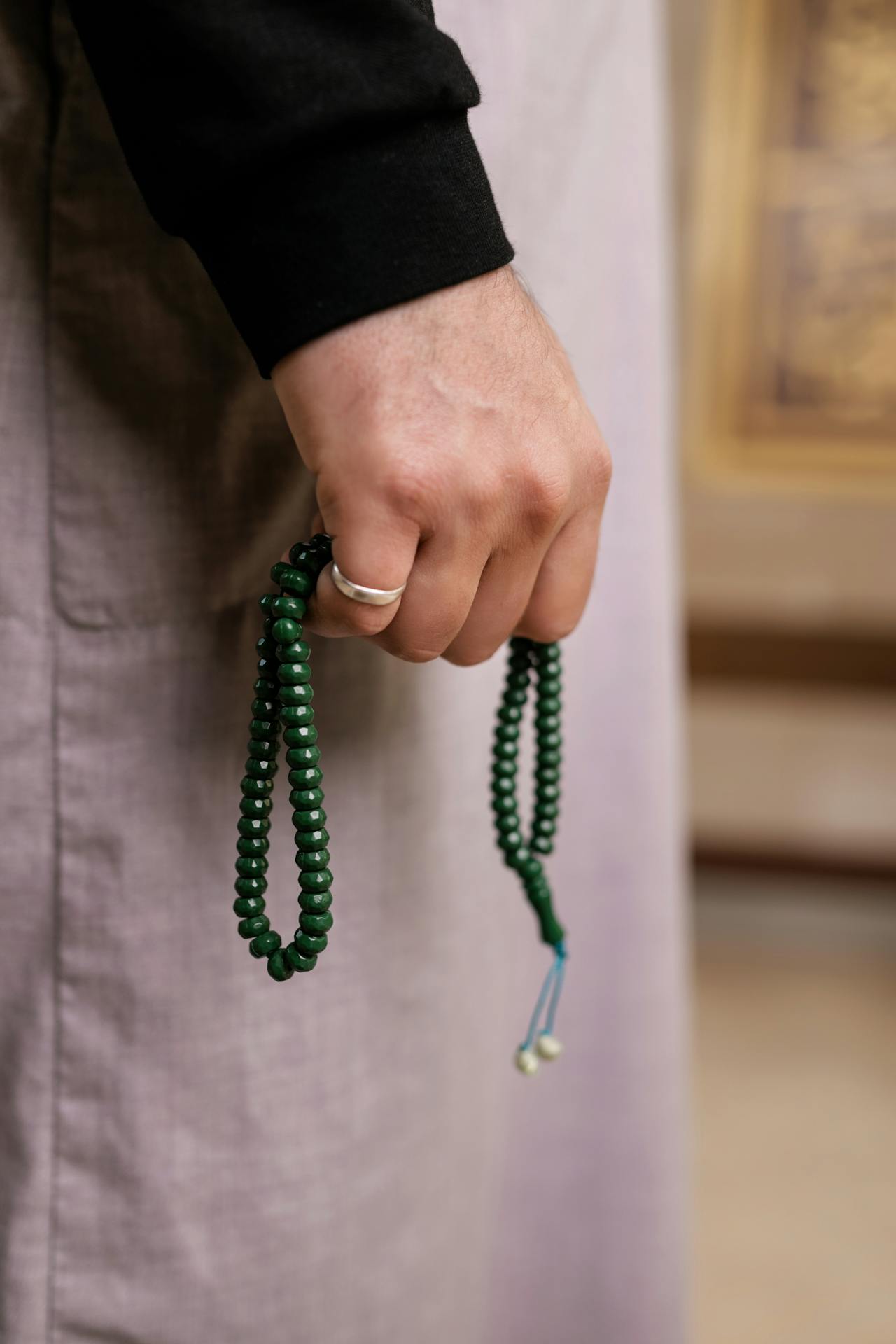 Close-up of green tasbih beads in hand for counting dhikr and Alhamdulillah recitation